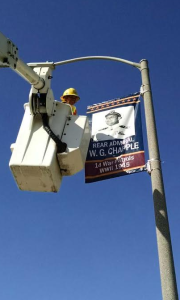 City employees, Caroline Ferreira and Luis Fernandez, hang the new banners along Third and Fourth Avenue of Heroes in time for Veterans Day.