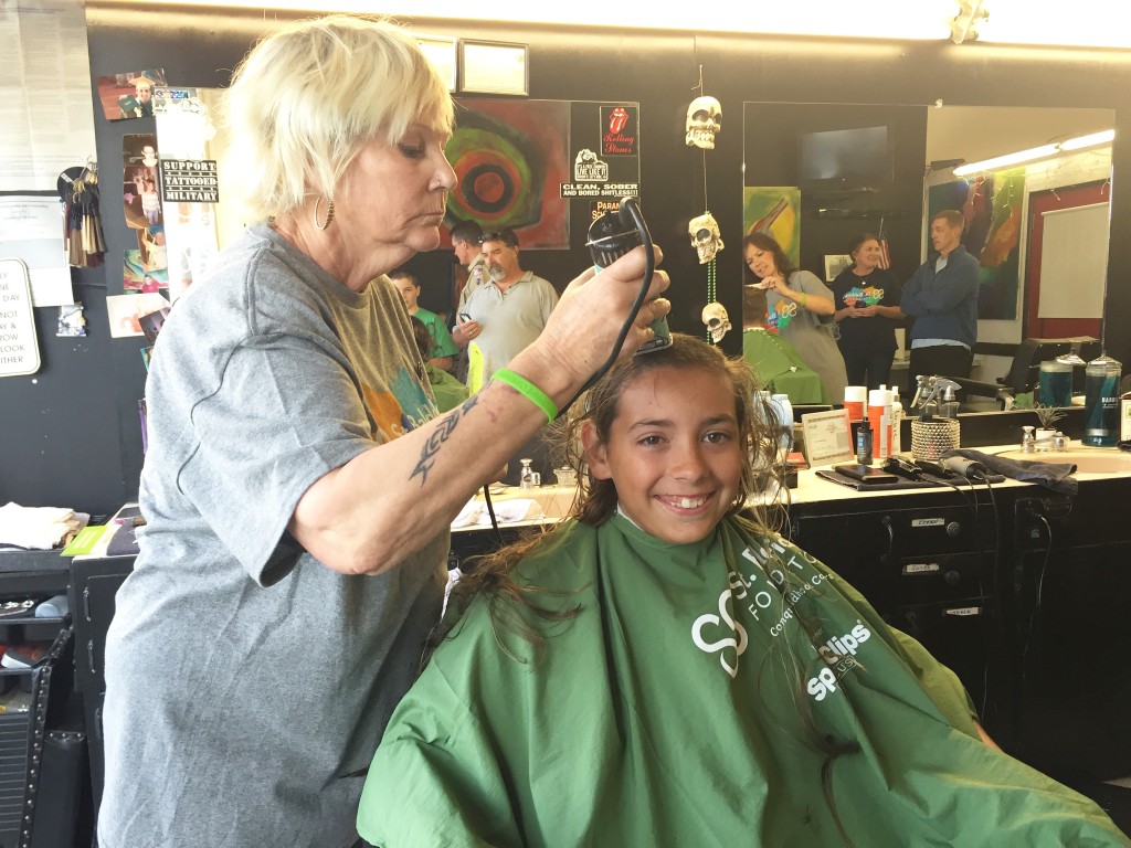 Sawyer Eader, getting his head shaved by Beth Abate, volunteered eight hours for the St. Baldrick's Foundation as part of his work toward his Citizenship in the Community Merit Badge.