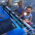 Two-kids-at-piano-smiling-big