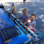 Two kids at piano smiling big